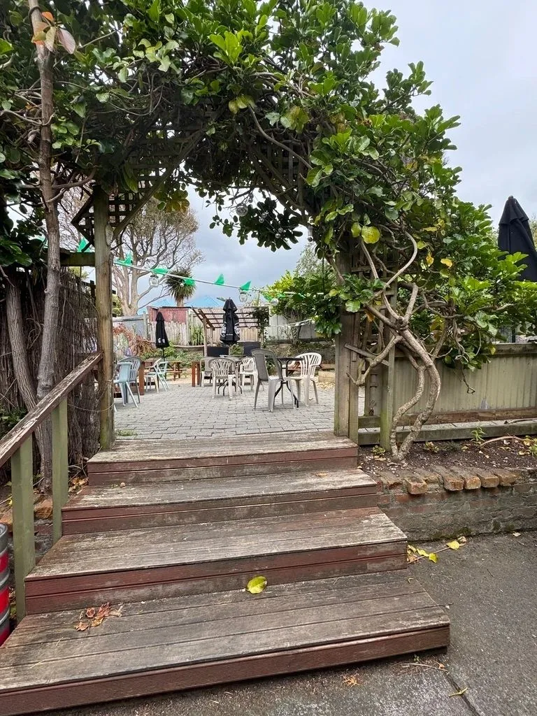 Wooden steps leading up to the garden under a leafy archway